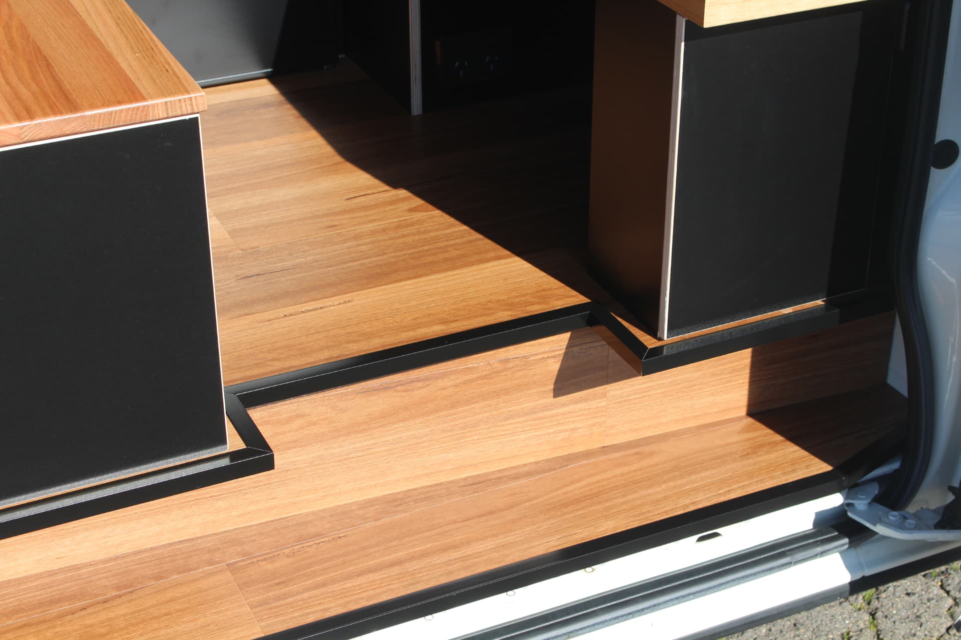 Hiace 200 Series Weekender — Hardwood floor and black joinery at the side door