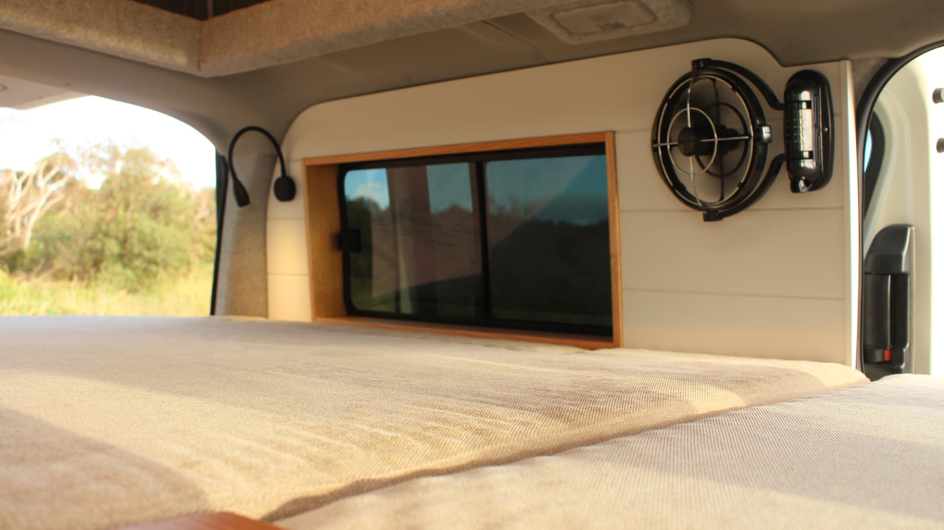 Custom van interior with timber-framed window and bed platform