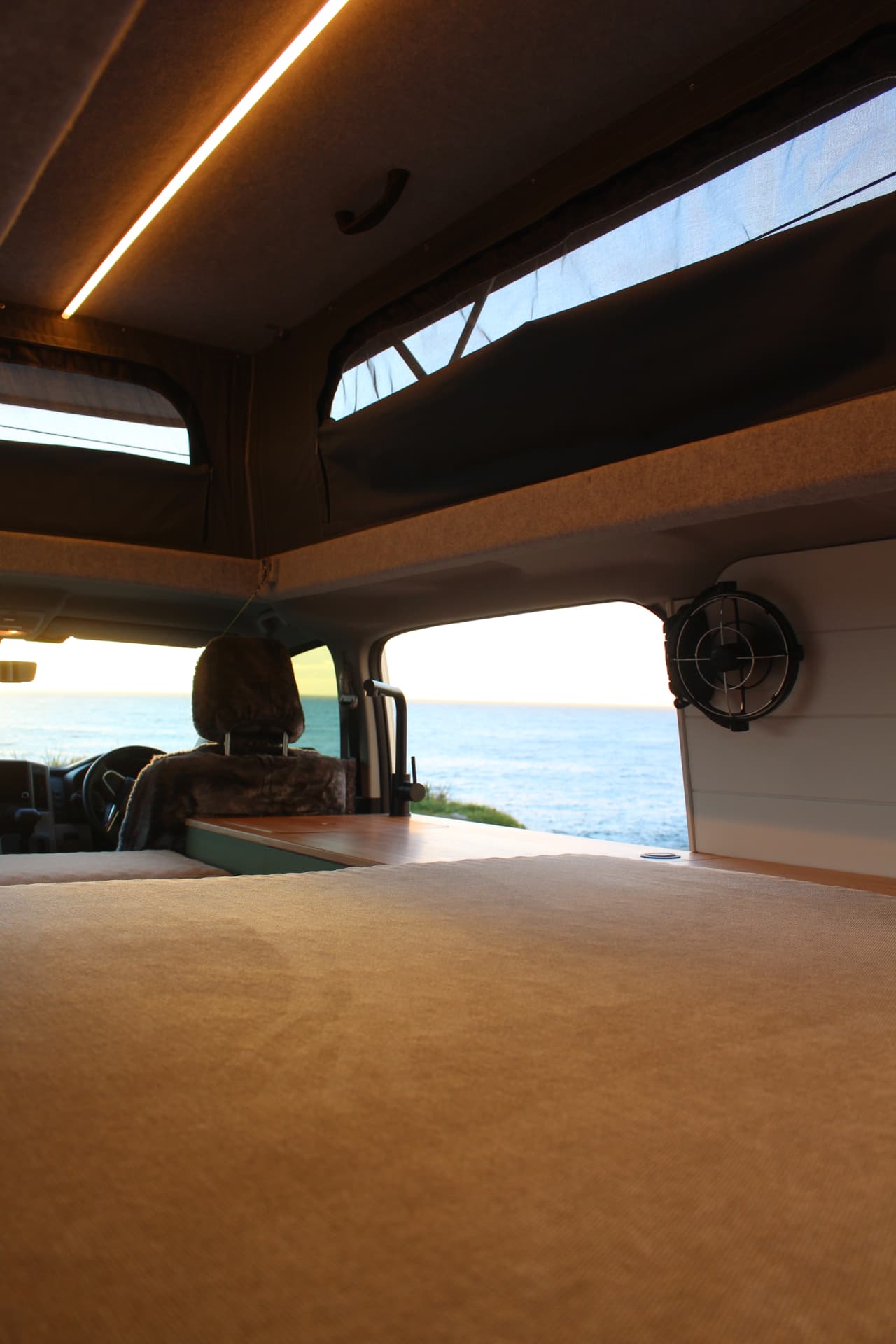 Toyota Hiace 300 Series — Inside the pop top with the ocean out front
