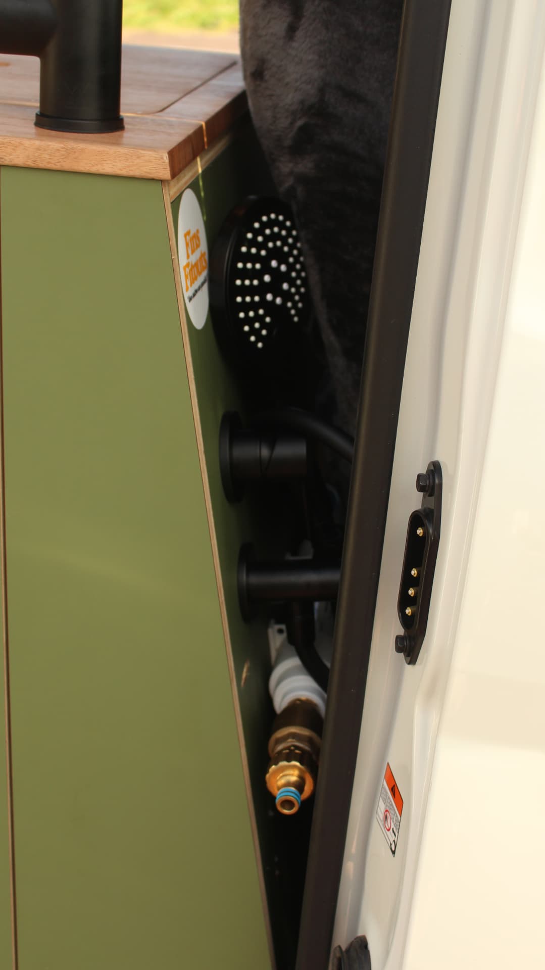 Toyota Hiace 300 Series — Shower head and hose stowed beside the kitchen