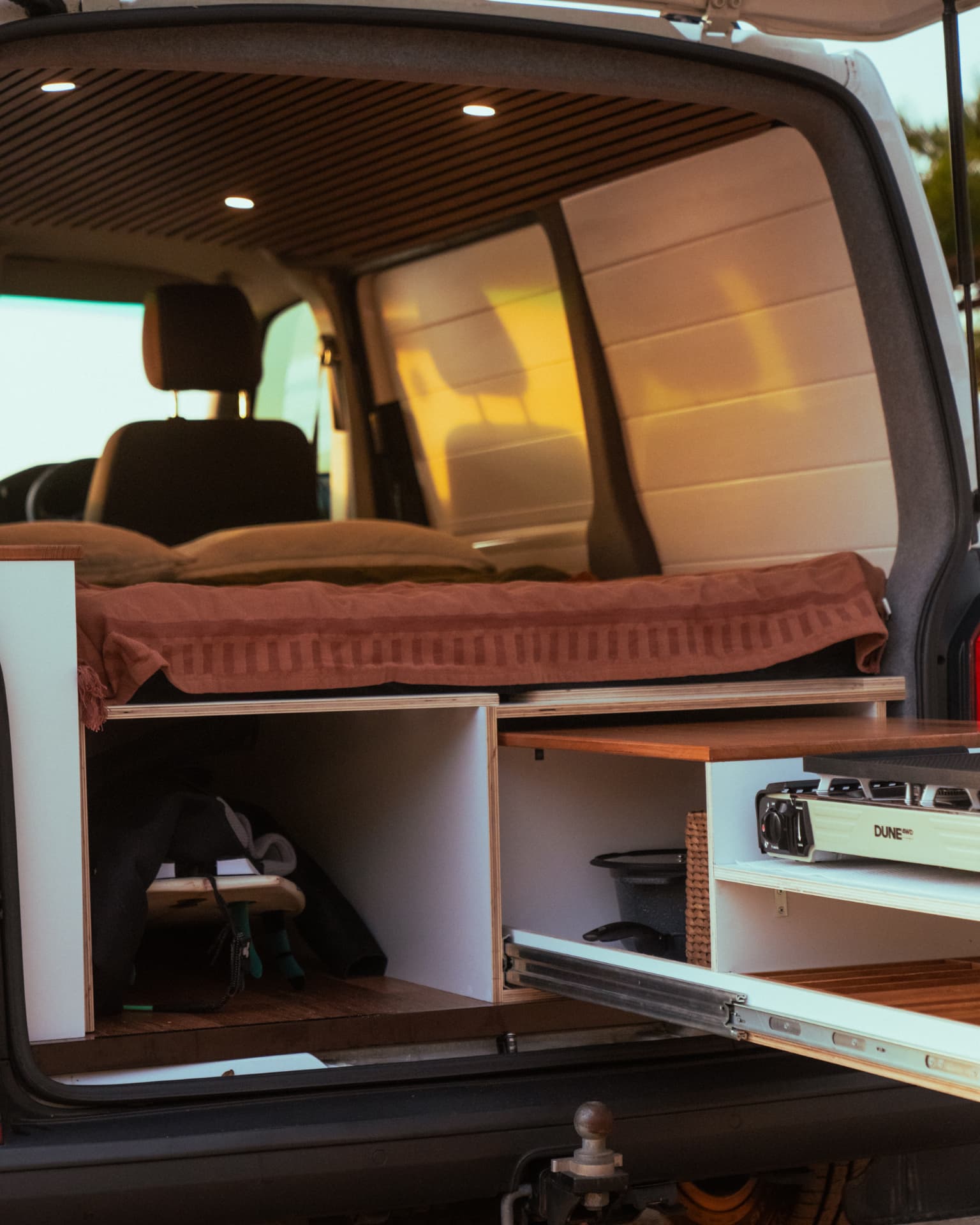 VW Transporter — Interior lit up at dusk with the kitchen pulled out