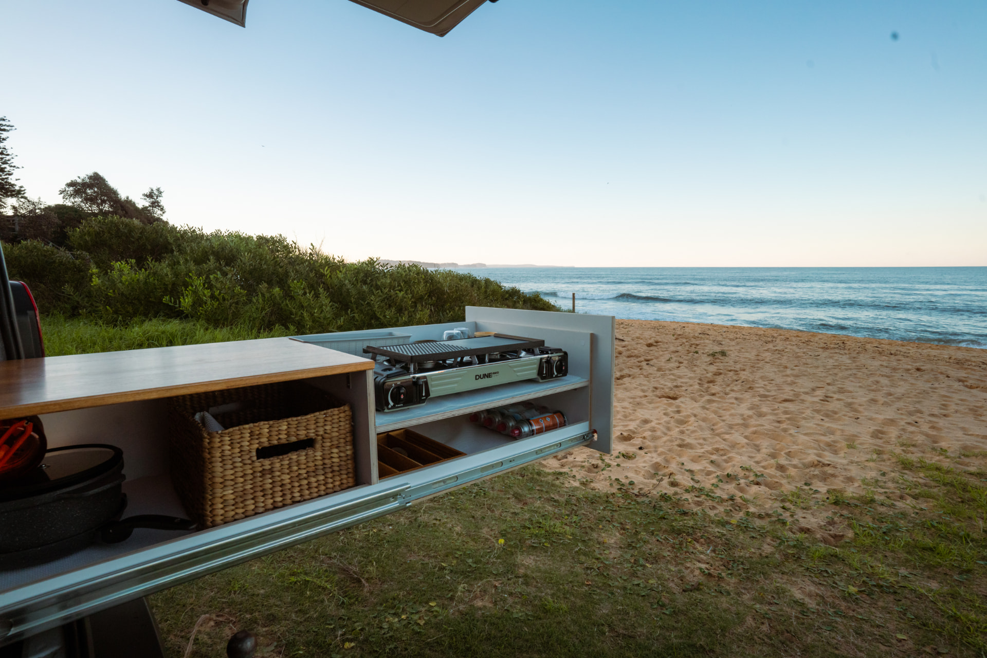 VW Transporter — Slide-out kitchen fully extended onto the dune grass