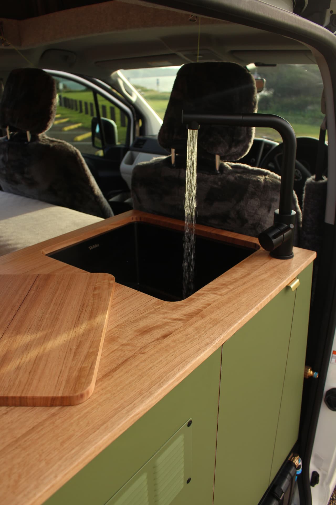 Toyota Hiace 300 Series — Chopping board beside the sink, water running
